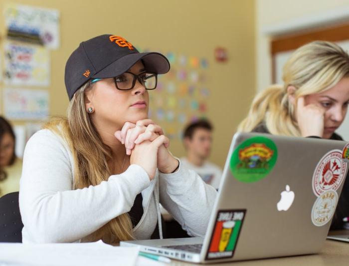 A student has her laptop open in front of her while she is listening to the professor